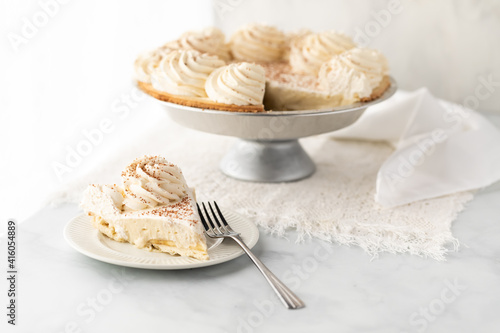 Fotografi A piece of banana cream pie against a bright window with a full pie in behind