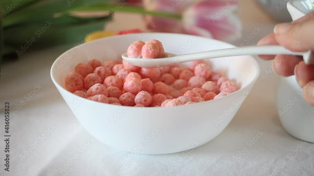 bowl with strawberry sweet corn balls. Delicious and healthy breakfast cereal. Human hand take a spoon and eating bowl with strawberry sweet corn balls. Delicious and healthy breakfast cereal. Human hand take a spoon and eating