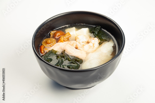 Miso soup with seafood in a black karelka. Ingredients broth, shrimp, salmon, perch, Tofu cheese, nameko mushrooms, miso paste, hondashi, wakame. For restaurant menu