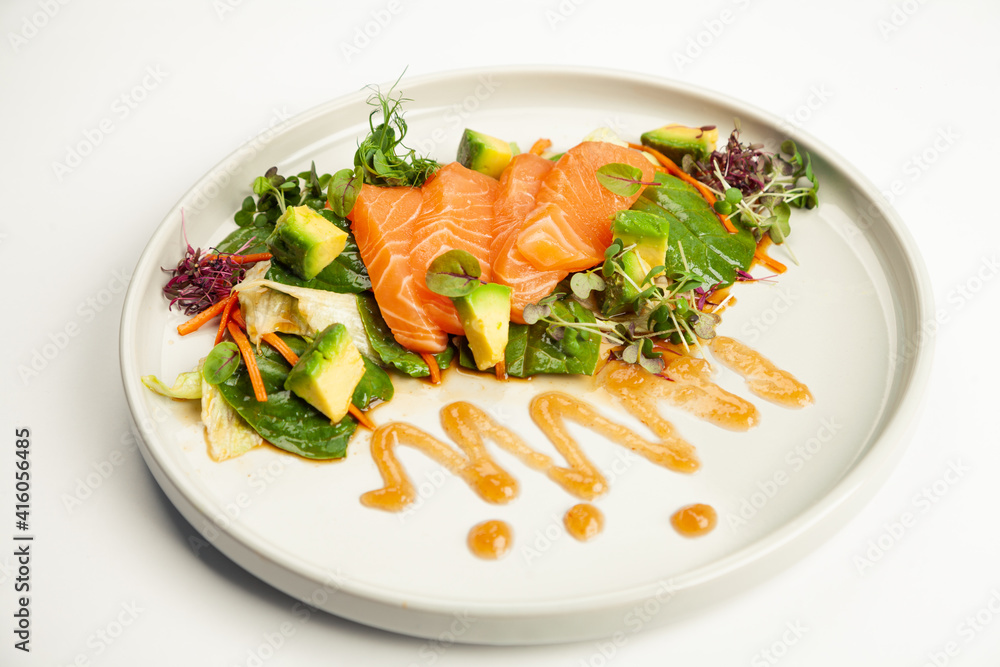 Salmon and avocado salad in tamarind sauce on a plate. Ingredients Iceberg lettuce, salmon, avocado, spinach, carrot, tamarind sauce. For restaurant menu Salmon and avocado salad in tamarind sauce on a plate. Ingredients Iceberg lettuce, salmon, avocado, spinach, carrot, tamarind sauce. For restaurant menu