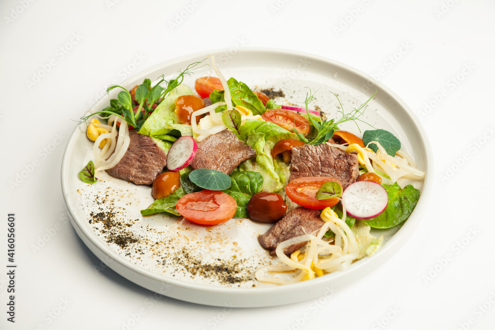 Salad with beef tataki on a plate. Ingredients Iceberg lettuce, tataki beef, nameko mushrooms, cherry tomatoes, moashi, spinach, ponzu sauce. For restaurant menu