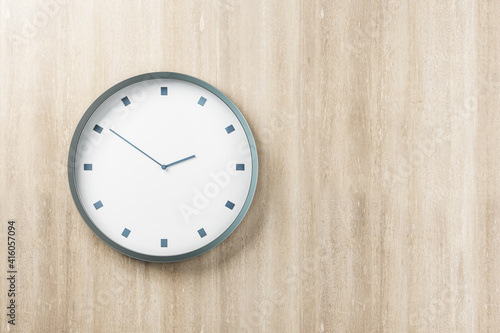 White round wall clock in metal frame on blank wooden wall with space for your logo. Mock up