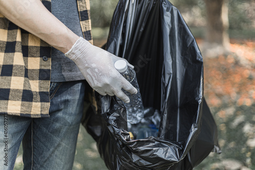 Male volunteers carry water bottles or plastic bags that have fallen in the park put them in trash cans, Environmental protection or volunteering for charity, Waste disposal through recycling.