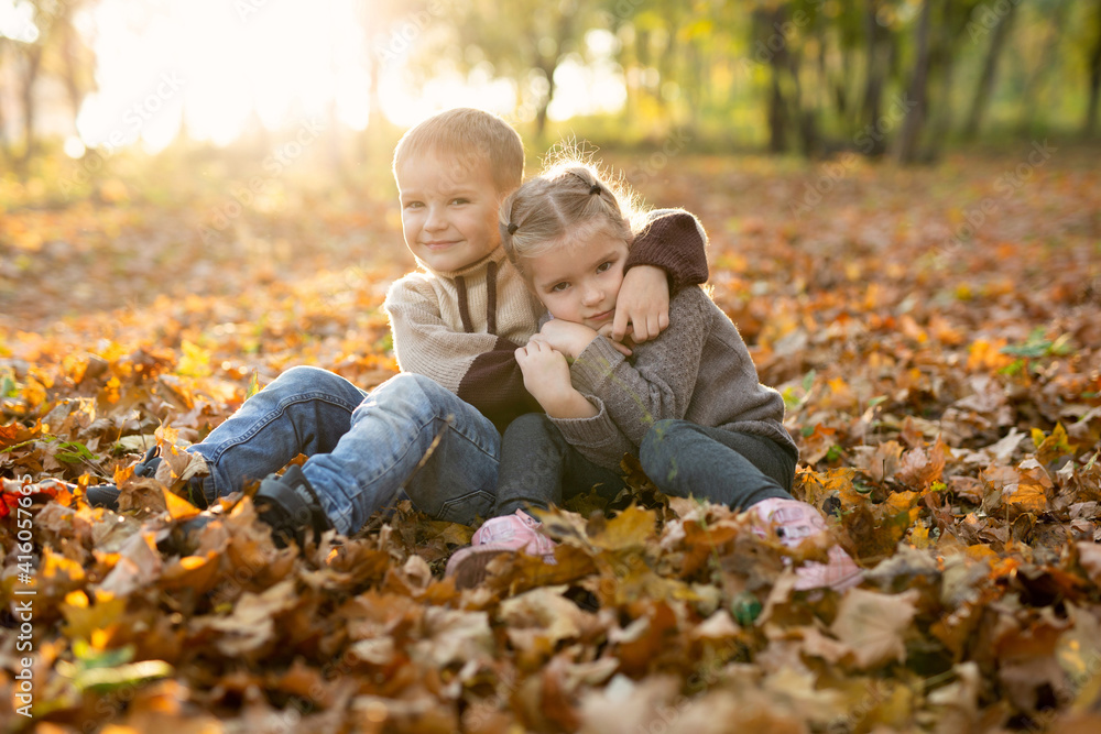 Cute children, boy and girl are playing, sitting and hugging together in autumn park. Cute children, boy and girl are playing, sitting and hugging together in autumn park.