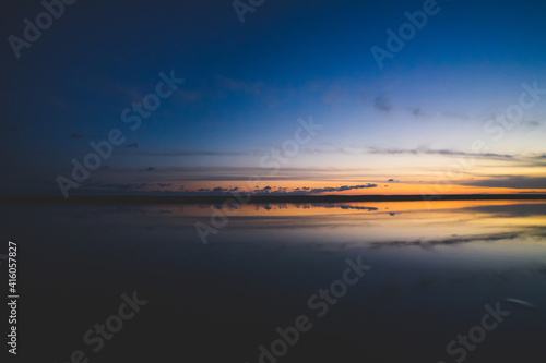 波の水たまりに反射した夕日と空と雲 © Kengo/ けんご