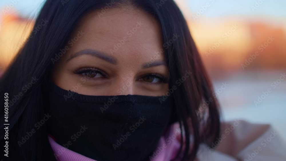 A girl wearing a black mask looks at camera and smiles. Nice winter afternoon. A girl wearing a black mask looks at camera and smiles. Nice winter afternoon.