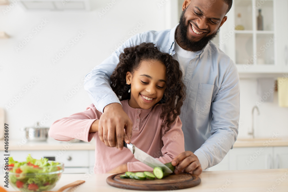 African american father teaching daughter how to cook salad African american father teaching daughter how to cook salad