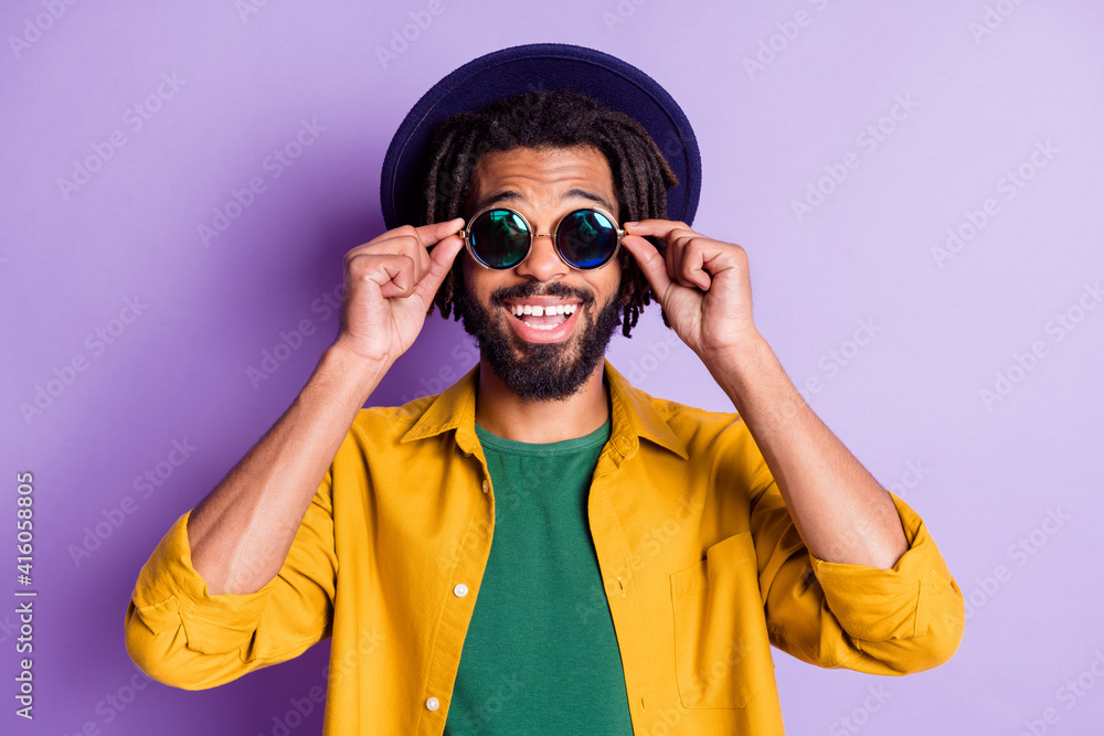 Photo of dreads hairdo dark skin person arms touch sunglass beaming smile isolated on violet color background