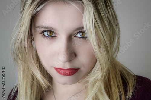 Portrait of a beautiful young blonde woman with red lipstick and intense gaze 