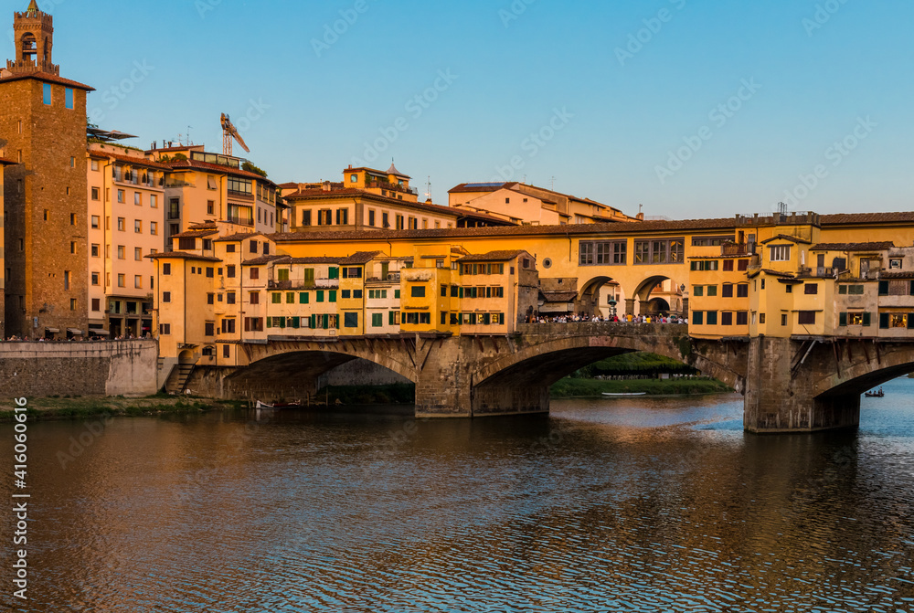 Picturesque close-up view of the famous bridge Ponte Vecchio over the Arno River in the historic centre of Florence at dusk. It is a medieval stone closed-spandrel segmental arch bridge.