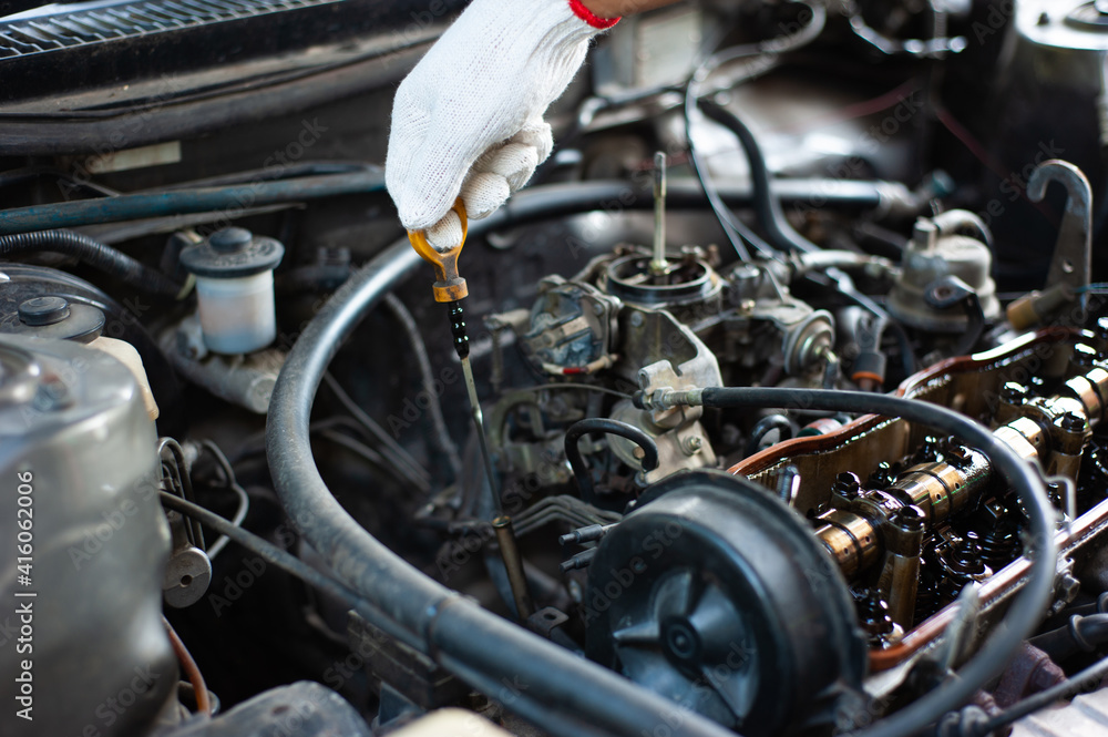 A mechanic checks the car and engine oil. A mechanic checks the car and engine oil.