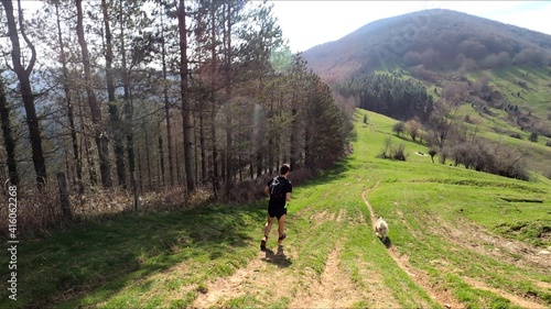 young man trail running in the mointains with his dog