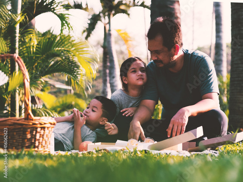 Asian family picnic at the park.Father and kids outing for picnic under sunliight in spring or summer. photo