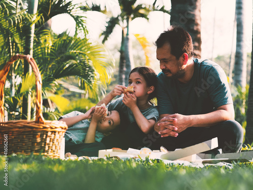 Asian family picnic at the park.Father and kids outing for picnic under sunliight in spring or summer. photo