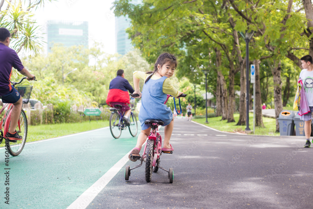 Fototapeta premium Little girl with bike in city public park nature recreation