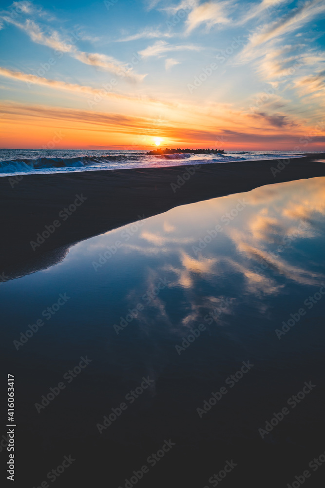 波の水たまりに反射した夕日と空と雲 波の水たまりに反射した夕日と空と雲