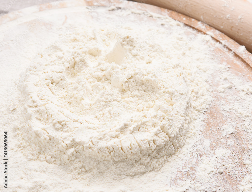 white wheat flour heaped on a round wooden board white wheat flour heaped on a round wooden board