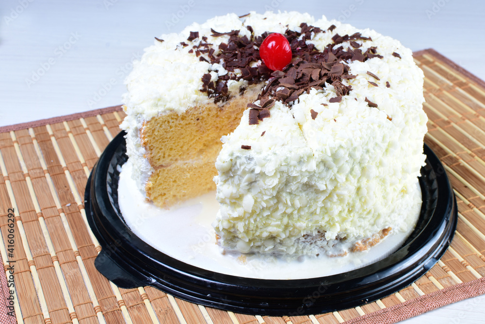 Cake decorated with vanilla and arequipe on white plate and light colored wooden background Cake decorated with vanilla and arequipe on white plate and light colored wooden background