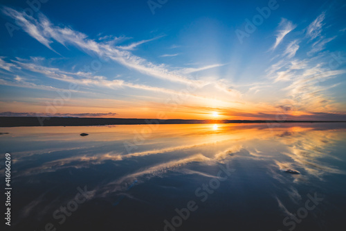 波の水たまりに反射した夕日と空と雲 © Kengo/ けんご