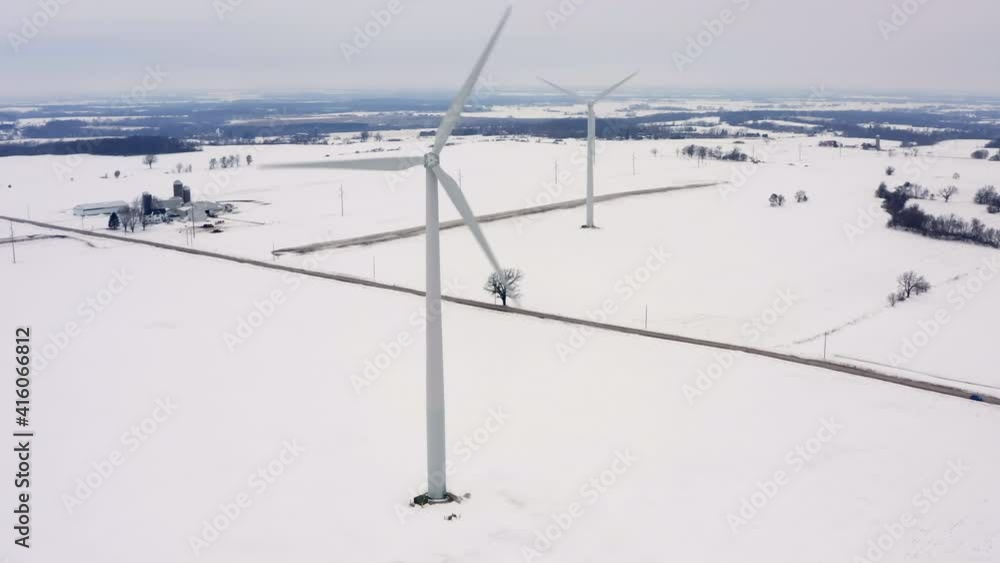 Aerial view of two wind turbine towers on countryside land covered by snow, winter scenery Aerial view of two wind turbine towers on countryside land covered by snow, winter scenery