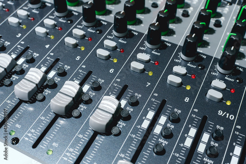 Closeup of a 16 channel digital stereo mixer - Focus on Channel faders and Aux knobs. Small recording studio setup. photo