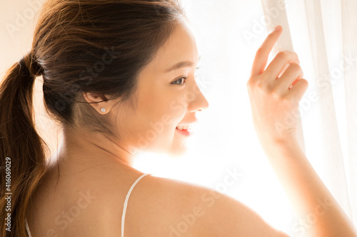 Young woman standing by the curtained window face closed up