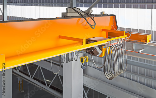 Overhead crane inside factory or warehouse. That industrial machinery or lifting equipment consist of hoist, hook and wire rope traveling on beam girder structure. For manufacturing production plant. photo