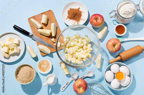 Cooking baking background with ingredients, fresh apples, spices and utensils on blue table.