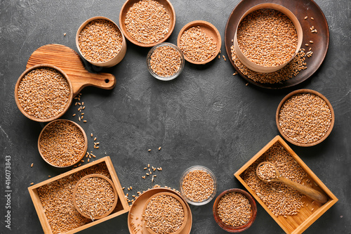 Frame made of bowls and boxes with wheat grains on dark background