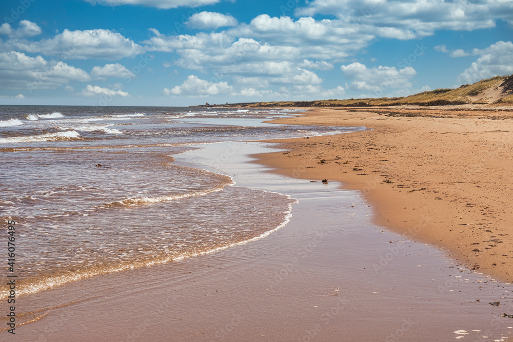 Waves lap up on a sandy beach on the north shore of Prince Edward Island, Canada.