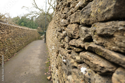 Old stone wall on side of a pedestrian walkway photo
