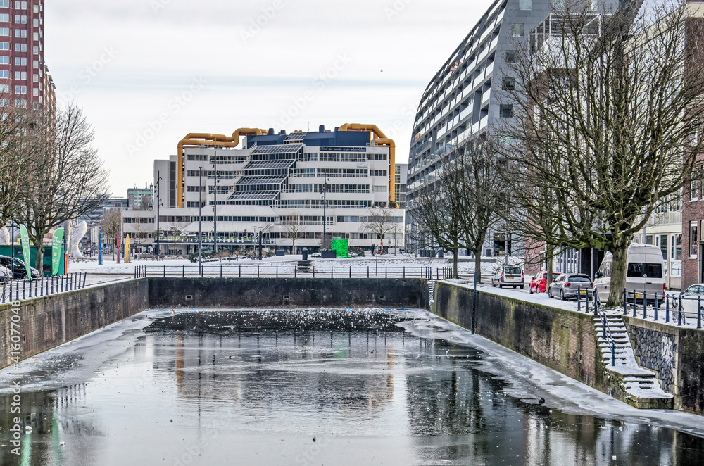 Naklejka premium Rotterdam, The Netherlands, February 14, 2021: snow and ice on and around Steigersgracht canal with the central library building in the background