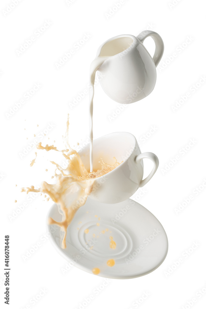 pouring milk and splashing milk tea from flying cup and saucer isolated on white background pouring milk and splashing milk tea from flying cup and saucer isolated on white background