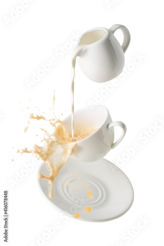 pouring milk and splashing milk tea from flying cup and saucer isolated on white background