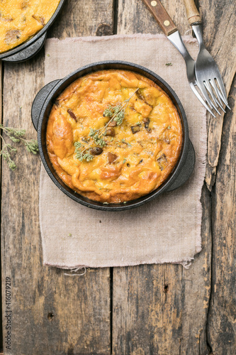 Frittata with mushrooms in a pan on wooden background. Fritata is an Italian breakfast dish.