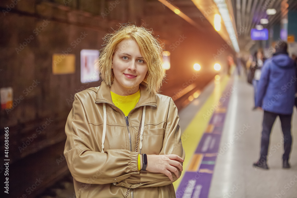 Young European woman is waiting for train on subway station platform.