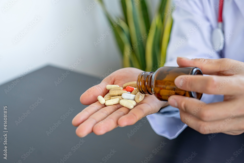 Pharmacist or doctor grasps a bottle of antibiotic capsule into your hand. To explain to the patient how much of the treatment is overdose On the black background table