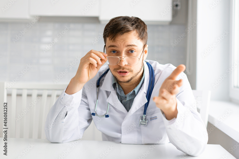 Portrait of a doctor with a stethoscope during a video communication consultation. He advises the patient about symptoms and treatment.