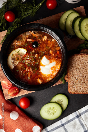 Photos hodgepodge soup on a wooden board with bread, cucumbers, tomatoes, herbs and nap