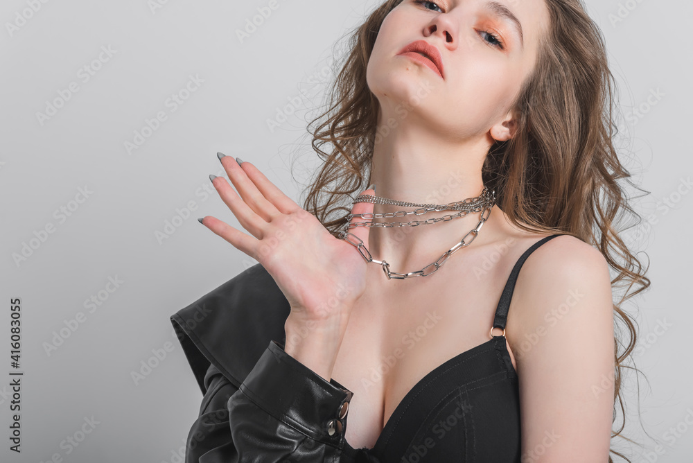 Beautiful girl with long hair in underwear and jewelry on a gray background. Concept of fashion shooting and advertising of lingerie