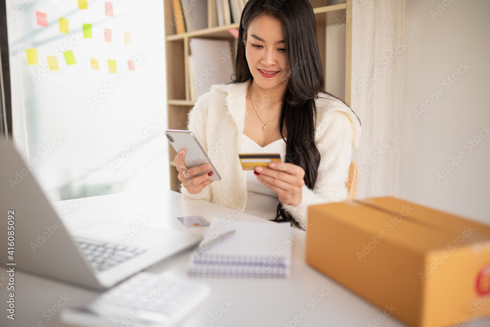 Portrait of Young woman using credit card,smartphone and laptop computer at home. Online shopping, e-commerce, internet banking, spending money, working from home concept Portrait of Young woman using credit card,smartphone and laptop computer at home. Online shopping, e-commerce, internet banking, spending money, working from home concept