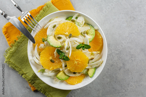 Oranges, fennel and avocado salad. On green and orange napkins. Grey background. Top view. Copy space.