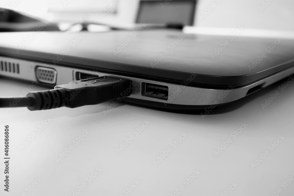 USB cable plugged in to laptop computer, close up USB cable plugged in to laptop computer, close up