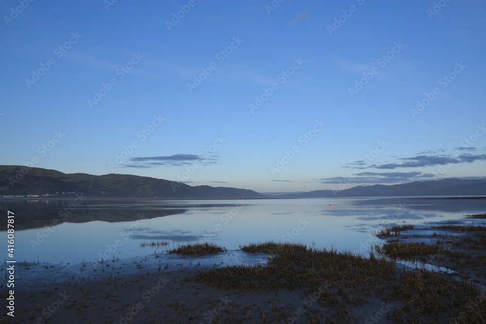 a view of the welsh mountains from ynyslas beach reflected in the estuary