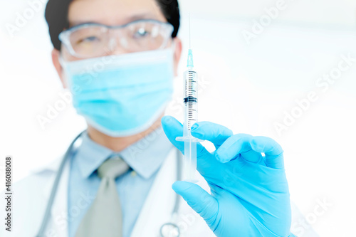Male doctor  holding syringe with needle up  getting ready to do injections and cure patients