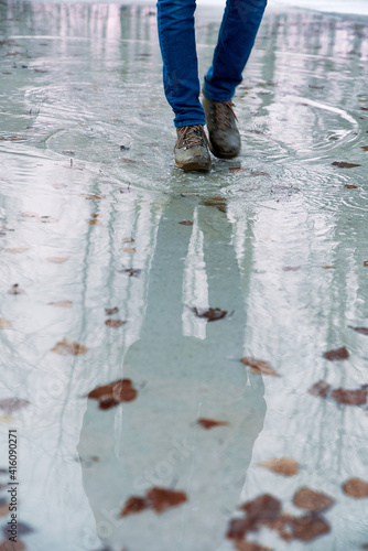 Boy teenager in boots jumps, runs through the puddles in the cold autumn