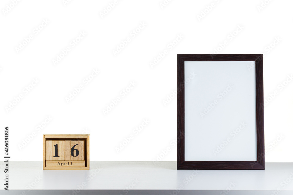 Wooden calendar 16 april with frame for photo on white table and background Wooden calendar 16 april with frame for photo on white table and background