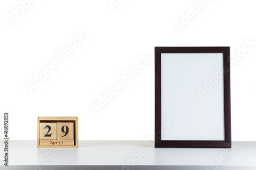 Wooden calendar 29 april with frame for photo on white table and background
