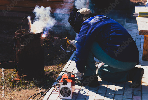 An experienced welder at work. Preparation and welding process of cast iron furnace. Selection focus. Shallow depth of field. Toned