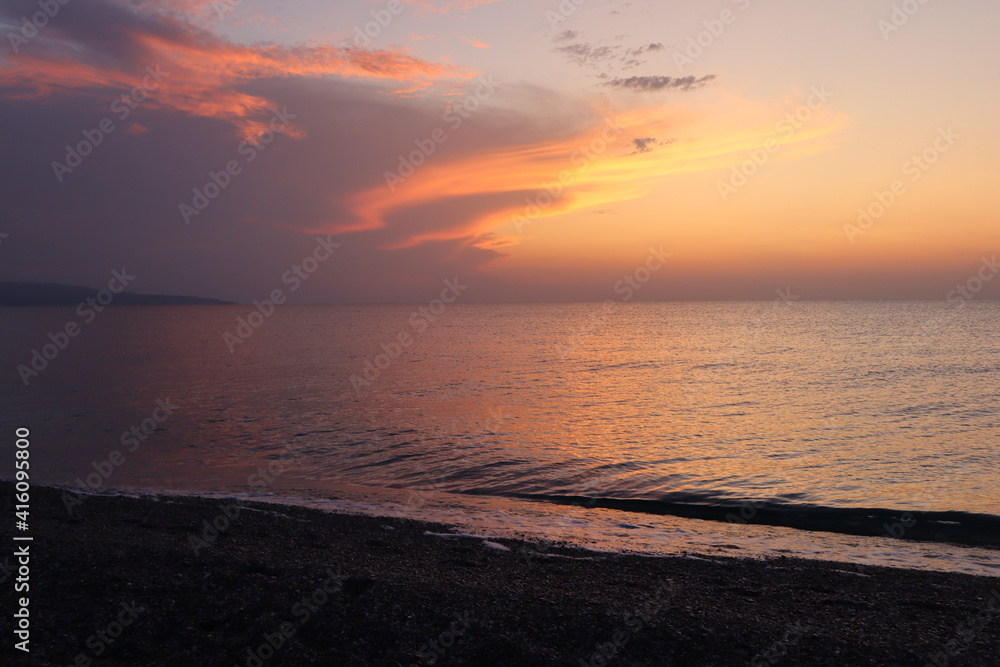 Seascape sunset on the seashore, lilac pink sky and sea